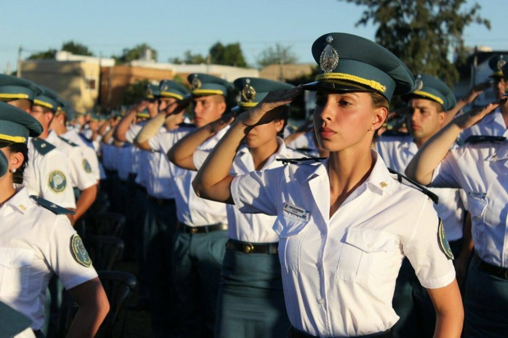 Cadetes con uniforme de ceremonia, gorra y camisa blanca, haciendo la venia